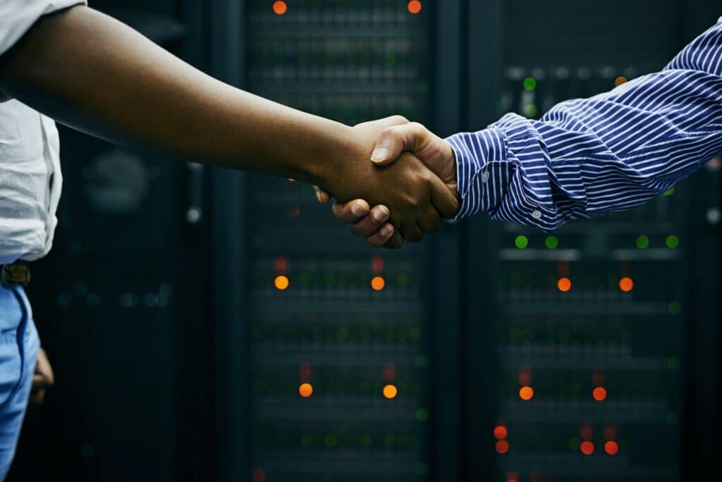 Paired up for professional IT service. Cropped shot of two men shaking hands in a data center.